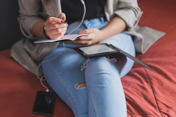 Young woman reading an electronic book. Taking notes of everything you learn.