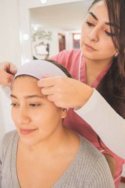 Genç bir kadın özel bir etkinlik için makyaj yapmaya hazırlanıyor. Makyaj merkezinde bugünün tadını çıkarırken.