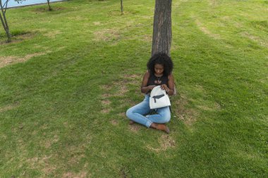 Afro-Amerikalı bir kadın şehir parkında yürüyor. Parkta muhteşem bir günün tadını çıkarıyorum..