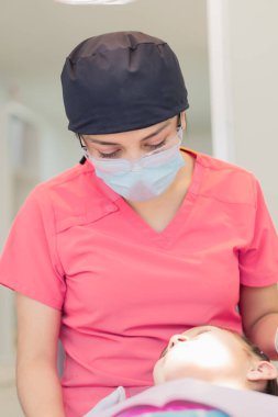 Bir dişçi muayenehanesinde diş tedavisi gören bir kız. Diş ve diş aletlerinizin bakımı için..