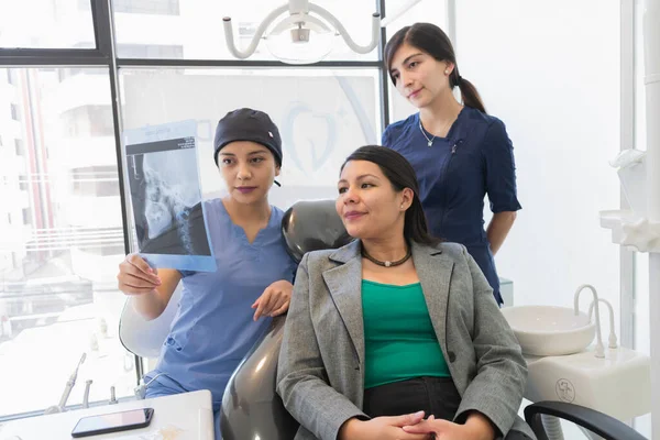 年轻的女牙医检查病人的X光片 教你要做的整个牙科手术 — 图库照片