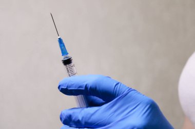 Aşılı bir şırınga, hastalıklara karşı bir enjeksiyon. Eldivenli bir doktor elinde şırınga tutuyor.