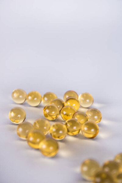 Многие желтые витамины лежат изолированные на белом фоне. Рыбное масло для здоровья