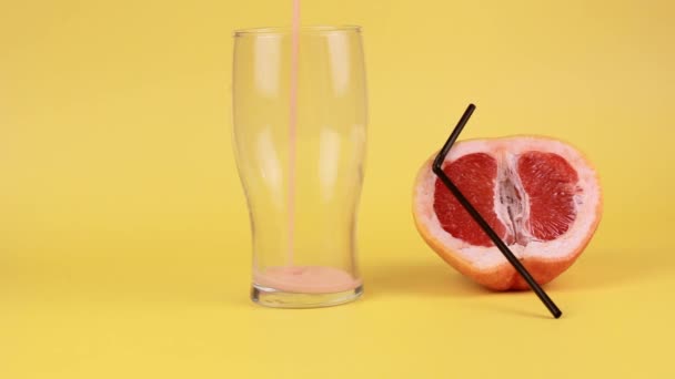 柚子冰沙倒入一个黄色背景的玻璃杯烧杯中 旁边躺着一颗柚子 上面有一根鸡尾酒稻草 — 图库视频影像