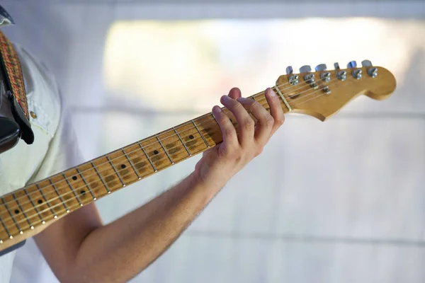 close-up detail of the musician's hands playing his electric guitar