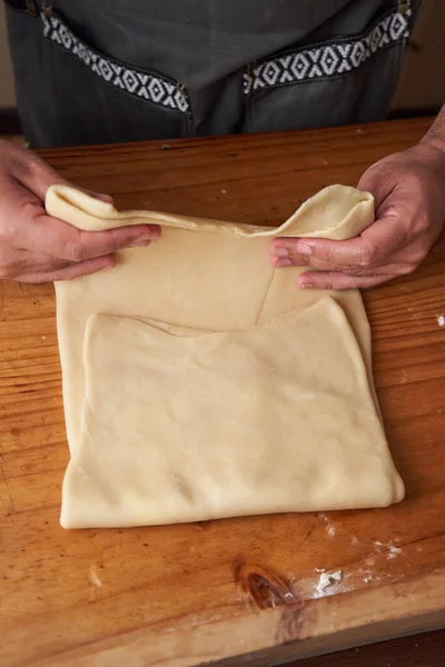 Aşçının elleri hazırlanmak için hamurunu katlar.