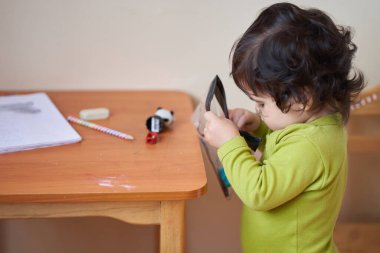 Yeşil tişörtlü çocuk kalem çizmek için elinde dikiş tutuyor. oyun etkinlikleri.