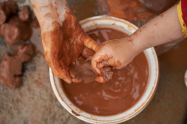 Kadın, bir çocuğu şekillendirirken ona kilden bir şey tutar. Kil figürleri modelleniyor