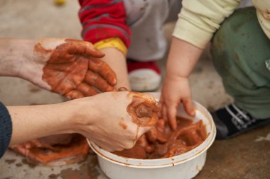 Kadınlar kil ve çocukları şekillendirmeden önce kil sıkar. Kil figürleri modelleniyor