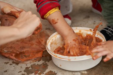 Çocuğun elleri çamurla suda oynuyor. Kil figürlerinin modellenmesi