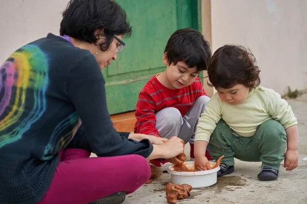 Kadın ve iki çocuk kil figürler yapar. Anne ve çocuklar kil kalıbı çıkarır. Evde çömlekçilik