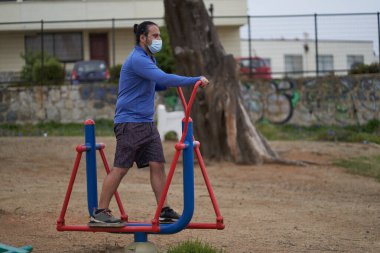 İnsanlar halka açık meydanda makineler üzerinde eliptik egzersizler yapıyor. Yeni normalde maske kullanımı. spor oturumu.