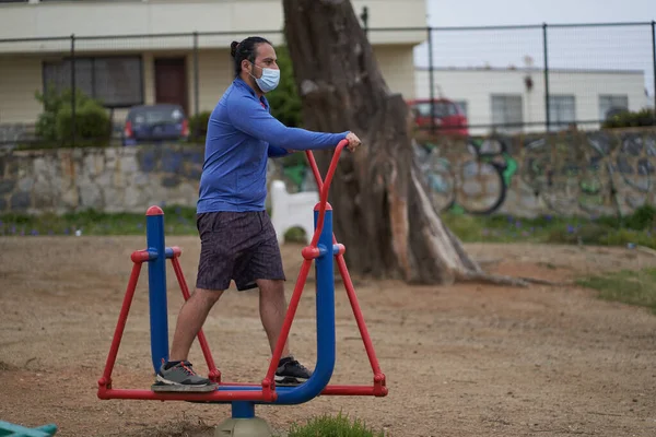İnsanlar halka açık meydanda makineler üzerinde eliptik egzersizler yapıyor. Yeni normalde maske kullanımı. spor oturumu.