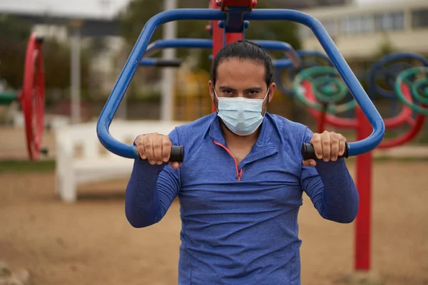 Yeni normal. Adam kameraya maske, maske ve spor kıyafetleriyle bakıyor. Parkta egzersiz yapan bir adam. Spor oturumu