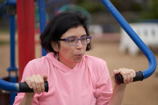 Şınav çeken kadın nefes veriyor. Pembe elbiseli kadın parkta egzersiz yapıyor. Spor oturumu