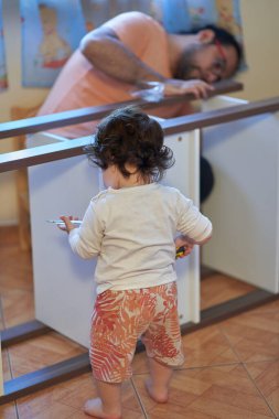 Oğlu evde ahşap mobilya montajı yaparken oynuyor. Marangozluk ve ebeveynlik oturumu