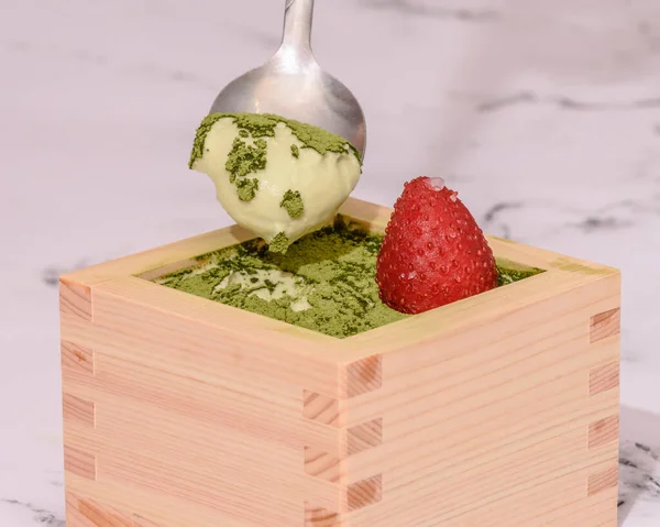 Çilekli Matcha Tiramisu Japon masu ahşap sake bardağının üstünde..