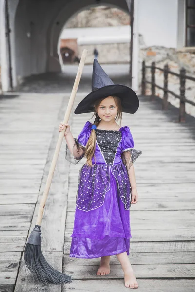 young sorceress stands with a broom in the castle