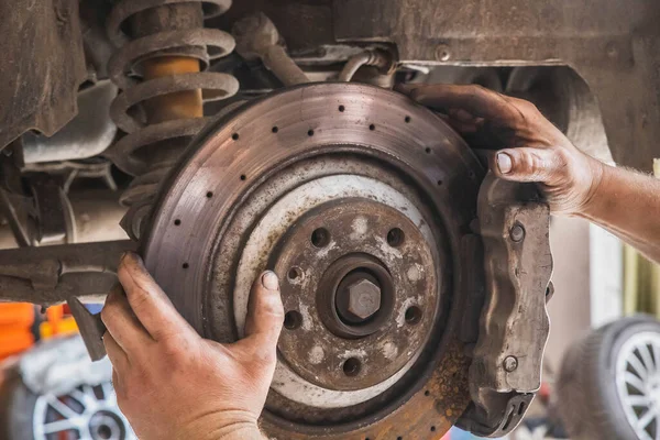 dirty hands worker changing car brakes in a workshop