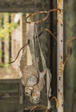 Eski gaz maskesi Pripyat okulundaki bir saksı standında asılı duruyor.