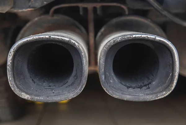 dual car exhaust pipe covered in soot