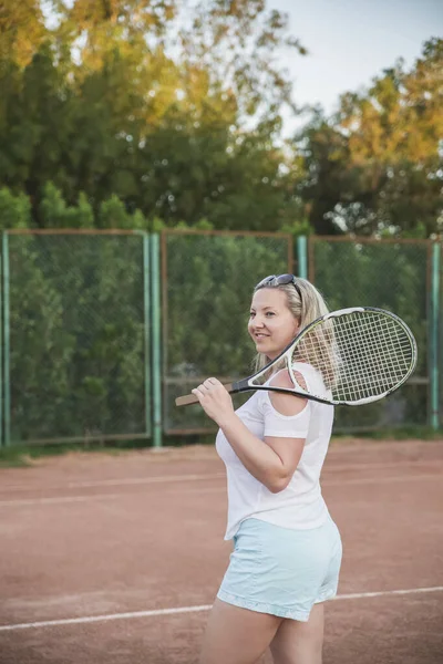 美丽的金发姑娘穿着蓝色短裤 站在运动场上打网球 — 图库照片