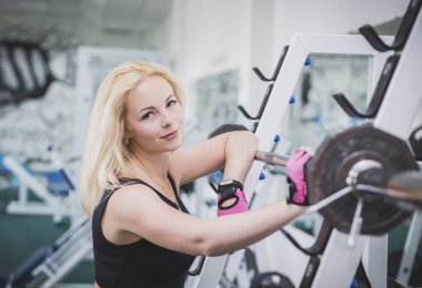 Çekici sarışın jimnastik salonunda çömelmiş duruyor.