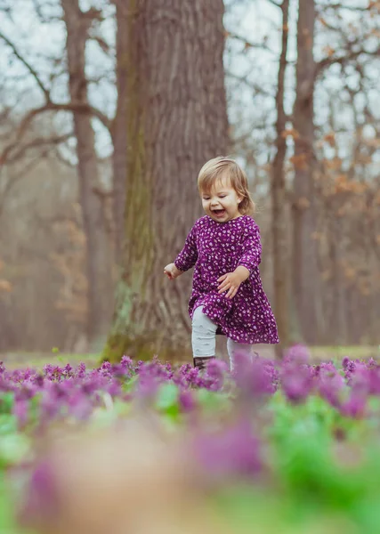 Ξανθό Μωρό Ένα Χρωματιστό Φόρεμα Τρέχει Ένα Ξέφωτο Δάσος Λουλούδια — Φωτογραφία Αρχείου