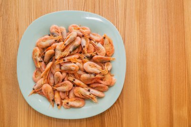 Ahşap bir masada karidesli mavi tabak.