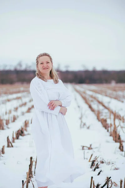 Barefoot woman in nightgown in winter field