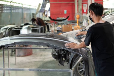 Bangkok, Tayland - 31 Ağustos 2017: Otomobil tamircisi veya araba tamircisi, tamirhanedeki veya tamirhanedeki tamir ve onarım sorunları için kaporta ve fiber tampon parçalarını kontrol edin ve tamir edin