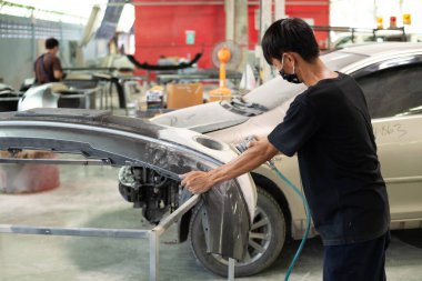 Bangkok, Tayland - 31 Ağustos 2017: Otomobil tamircisi veya araba tamircisi, tamirhanedeki veya tamirhanedeki tamir ve onarım sorunları için kaporta ve fiber tampon parçalarını kontrol edin ve tamir edin