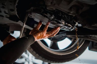 Araba tamircisi eski otomatik şanzıman sıvısını (ATF) ya da araba garajında vites kutusu motorunun yağını değiştirmek için vites yağını boşaltır.
