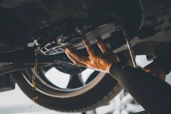 Araba tamircisi eski otomatik şanzıman sıvısını (ATF) ya da araba garajında vites kutusu motorunun yağını değiştirmek için vites yağını boşaltır.