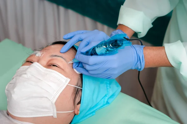 Tatuaje Ceja Mujer Asiática Por Especialista Médico Clínica Del Tatuaje Imagen De Stock