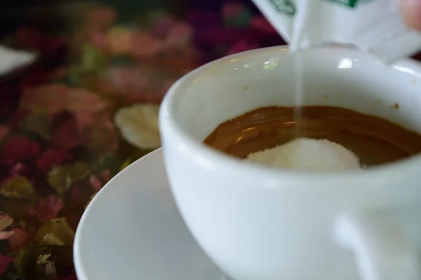 Inunden la crema en el café sobre la mesa con la flor — Foto de Stock
