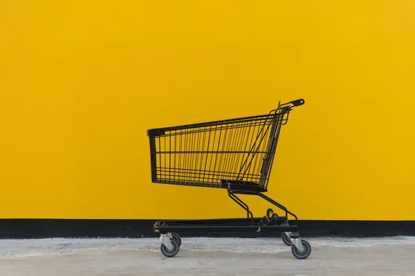 Estilo minimalista, carrito de compras y pared amarilla . — Foto de Stock