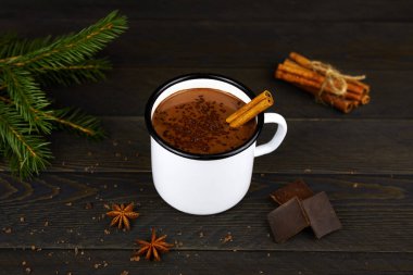 Siyah ahşap arka planda beyaz bir diş mineli fincanda tarçınlı ev yapımı sıcak çikolata..