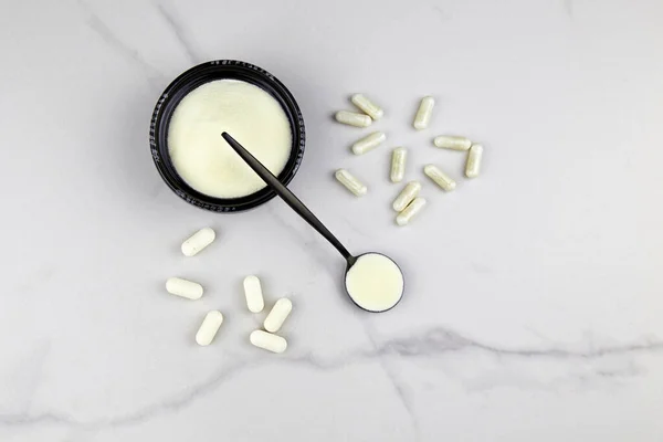 Kolajen protein tozu ve kapsüller gri arkaplanda. Cilt, kemik ve eklemler için doğal güzellik ve sağlık desteği.