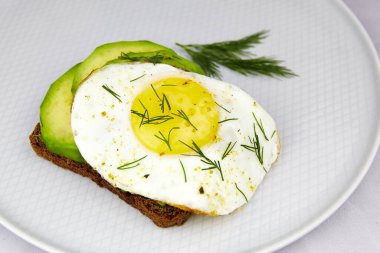 Avokadolu sandviç ve tabakta sahanda yumurta, yakın çekim. Sağlıklı kahvaltı ya da atıştırmalık.