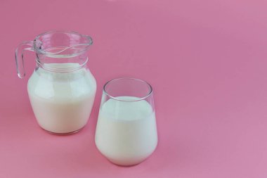Organik probiyotik kefir veya yoğurt, bardakta probiyotikler ve pembe arka planda bir sürahi. Ev yapımı soğuk mayalanmış süt içeceği..