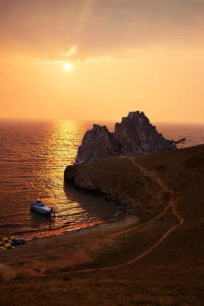 Baykal Gölü 'nde gün batımı. Şaman kayası için güzel bir manzara ya da Olkhon adasında bir yaz akşamı Burkhan Burnu. Gölün körfezinde turistlerle dolu bir tekne..
