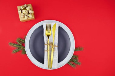 Noel sofrası. Kırmızı arkaplanda hediye ve çatal bıçak takımı.