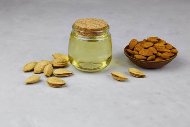 Cam kavanozda badem yağı ve arka planda fındık. Yemek pişirmek için vejetaryen yağları.