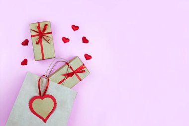 Kırmızı hediye çantası ve pembe arka planda dekorasyon kalpleri. Sevgililer Günü, Doğum günü, Anneler Günü 