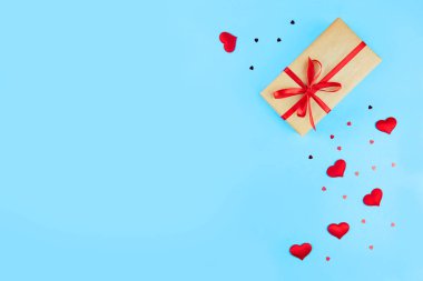 Sevgililer Günü geçmişi. Hediye, kırmızı kurdele, dekoratif kalpler, mavi arka planda konfeti. Sevgililer Günü Konsepti. Kutlama pankartı ya da kartpostal. Düz konum, üst görünüm, kopyalama alanı