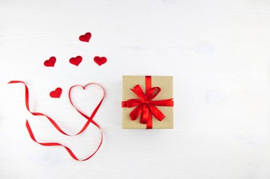 Kırmızı kurdeleli ve beyaz arka planda kalp şeklinde kurdeleli el işi kağıt ambalajlı hediye kutusu. Sevgililer Günü, Anneler Günü, Doğum günü, Noel.
