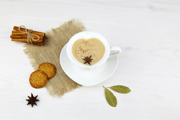 A cup of masala tea and cookies. Traditional Indian tea drink with milk and spices. Close-up.