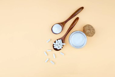 Açık sarı zemin üzerinde kolajen protein tozu ve kapsüller. Cilt ve eklemler için beslenme desteği.