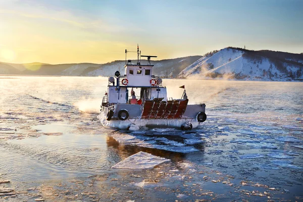 Beautiful sunset on Lake Baikal in spring. Melting ice and open water in the lake. The ferry ferries passengers and tourists to the other side of the lake.